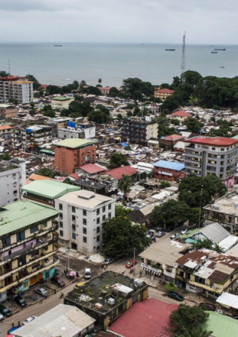 Shipping vessels sit on the waterway beyond commercial and residential buildings on the city skyline in Conakry, Guinea, on Saturday, Sept. 5, 2015. While Guinea produces bauxite, which is refined into aluminum, and has vast iron-ore deposits, its mining potential has been largely untapped because of political instability and a lack of infrastructure. Photographer: Waldo Swiegers/Bloomberg via Getty Images